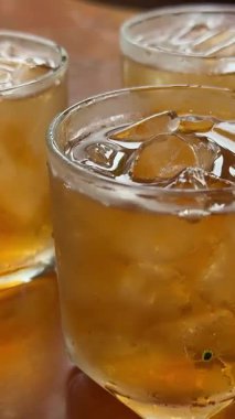 Çay seremonisi. Buzlu çay şeffaf bir bardağa dökülür. Buz küpleri, limon dilimleri ve parlak arka planda duran nane şekeri ile. Modern soğuk Çin töreni. Üç buzlu içecek, yeşil buzlu çay.