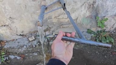 Uzaktan kumandalı musluk suyu için eski bir duvara monte edilmiş musluk. Bir adamın eli eski bir musluğu açar. Yüksek kalite 4k görüntü