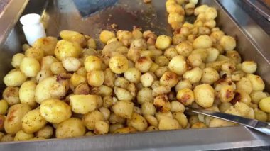 Bir restoranda, açık büfede, bir spatulayla müşterilere sunulan küçük, yuvarlak, soyulmuş patatesler. Yağlı gıda nişastası. Sebzeleyebildiğiniz kadar sebze. Yüksek kalite 4k görüntü