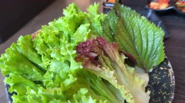 Bir tabak vejetaryen yemeğindeki sulu taze salata marul fesleğenini sağlıklı beslenme düzenini masa yemeği restoranında yapar. Yüksek kalite 4k görüntü