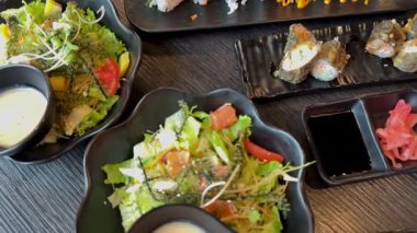 Masa siyah metali, Asya mutfağı salataları, suşi baharatları deniz ürünleri sebzeleri ve Japon restoranının açık büfe ziyafeti gibi ağır çekimler sundu. Yüksek kalite 4k görüntü