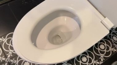 Jantsız bir klozet kapağında sifonu çekme işlemi. Dolly sürgülü çok yakın plan. Su bir spiral içinde döner. Evdeki kirli sifonu çek ve otur. UHD. Yüksek kalite 4k görüntü