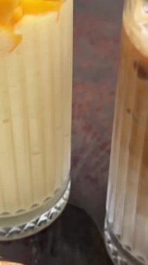 Kafedeki masada iki bardak mango smoothie ve buzlu mağara ve muz lifiyle şerbetli kahvenin kahvaltısı tropikal hava şekerlemeleri. Yüksek kalite 4k görüntü