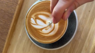 Latte sanatı yapılıyor. Cafe 'de yapılan kahve sanatının yakın çekim videosu. Süt, beyaz bardağa kahve ile dolduruluyor ve güzel bir latte sanatı yaratıyor. Yüksek kalite 4k görüntü