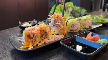 Kamera Hareketli Suşi Parçalarının Üst Manzarası. Taze Japon suşisi, Asya mutfağı konsepti. Topladığı insanlar. Kara Taş Masa 'ya yerleştirilmiş. Kamera Hareket Kontrolüne Yerleştirildi 