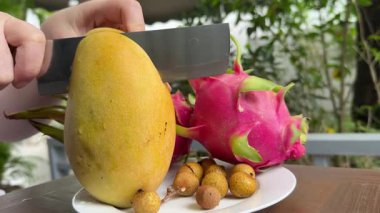 Üstünde koca bir mango olan bir tabak mango dilimi. Mango dilimi küçük parçalara bölündü. Yüksek kalite 4k görüntü