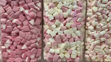 Makro, bir tepsi yumuşak fıçı şeklindeki, pembe ve beyaz şekerlemeli şekerleme yığınının yavaş çekimini yapıyor. Yüksek kalite 4k görüntü