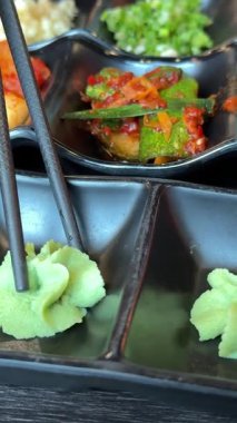 Özellikle siyah yemek çubukları, baharatlar, Asya yemeklerine katkı maddeleri, yeşil baharatlar, siyah masa restoranındaki bir kafede. Yüksek kalite 4k görüntü