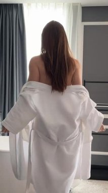 Kız bornozunu çıkarıyor. Beyaz pamuk havluya sarılmış beyaz kadın kadın kadın kadın. Banyo küvetinde yıkanmaya hazırlanıyor. 