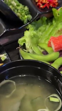 Yeşil soğanlı serpinti yeşil soğanlı miso çorbası siyah tabak suşi sebzeli Japon Asya restoranında. Yüksek kalite 4k görüntü