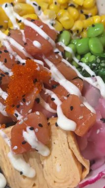 Yüksek açılı çekim, suşi alma seçenekleriyle dolu iki kağıt kaseyi gözler önüne seriyor. Kızarmış suşi sosislileri ve tobiko ile karides dürümleri de dahil. Kırsal ahşap bir bankta.. 