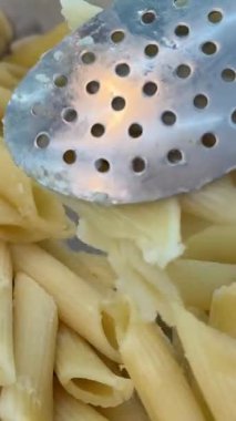 Taze pişmiş fettuccine cömert bir servis siyah bir tabakta sergilenir. Mutfak temiz ve modern bir estetiğe sahip. Arka planda mutfak aletleri ve malzemeler var. Yüksek kalite 4k görüntü