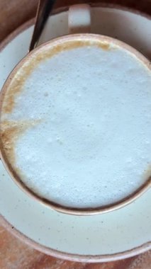 Latte sanatı yapılıyor. Cafe 'de yapılan kahve sanatının yakın çekim videosu. Süt, beyaz bardağa kahve ile dolduruluyor ve güzel bir latte sanatı yaratıyor. Yüksek kalite 4k görüntü