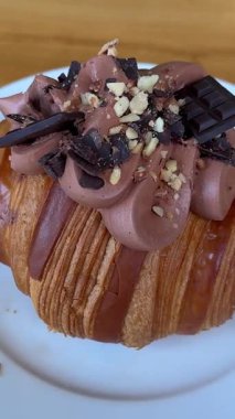 Çikolata parçacıklı kruvasan beyaz bir tabakta yatıyor. Düz yatıyordu. Yüksek kalite 4k görüntü