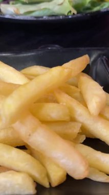 Kızartmaları mayonezin içine daldıran bir el ve yumuşak ışığın altında çizgili bir tabakta ketçap. Yüksek kalite 4k görüntü