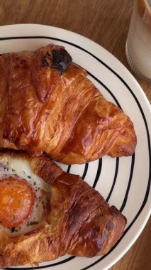 Lezzetli kokulu kahvaltı buzlu kahve ve içinde yumurta olan kruvasan kahveci restoranının kahveli pastalı kahvesinde beyaz bir masada. Yüksek kalite 4k görüntü