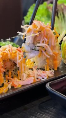 Kamera Hareketli Suşi Parçalarının Üst Manzarası. Taze Japon suşisi, Asya mutfağı konsepti. Topladığı insanlar. Kara Taş Masa 'ya yerleştirilmiş. Kamera Hareket Kontrolüne Yerleştirildi 