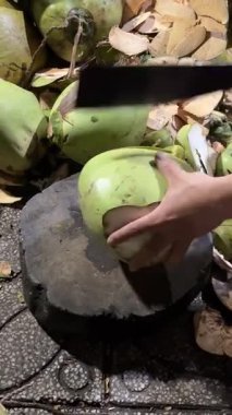 Geleneksel bir bıçakla hindistan cevizi kesme. Bir adam taze hindistan cevizi kesmek için özel bir hindistan cevizi bıçağı kullanıyor. Ayrıntılı işlem: bıçaklama ve ayırma 