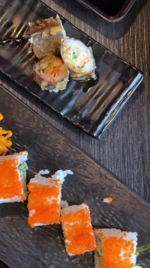 Kamera Hareketli Suşi Parçalarının Üst Manzarası. Taze Japon suşisi, Asya mutfağı konsepti. Topladığı insanlar. Kara Taş Masa 'ya yerleştirilmiş. Kamera Hareket Kontrol Sistemi 'ne Yerleştirildi