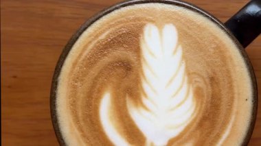 Mavi seramik bardakta güzel latte sanatıyla kapuçino ve güzel bir latte sanatı. Öğle yemeğinde leziz kahvenin dikey videosu. Yüksek kalite 4k görüntü