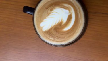 Latte sanat kahvesi makroya dönüşür, sanat kahvecisi kahve fincanında kahve yapar, müşteriye de kafe tezgahında kahve yapar. Erkek kahveci garson müşteriye sütlü sıcak içecek servisi yapıyor. Küçük işletme