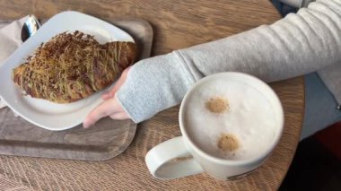 Bir kafede Fransız kruvasanını kıran bir kadın eli. Yüksek kalite 4k görüntü