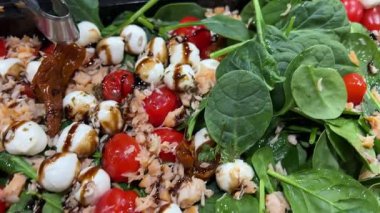 Caprese kanepelerine kiraz domatesli ve mozzarella peynirli peynir toplarıyla balzamik sos dökmek. Yüksek kalite 4k görüntü