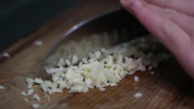 Yong Man 'in aşçısının önü ince sarımsak dilimlerini kesme tahtasında bıçakla kesiyor. Doğal ışıkla yakın çekim. Yüksek kalite 4k görüntü