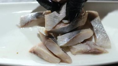 Tabakta ringa balığı servis et. Restoranda yemek pişir. Temizlenmiş filetolar tabakta parçalara ayrılsın. İsteyen istemciye sunmadan önce aperatif sunumunun son detaylarını tamamlayan dikkatli usta