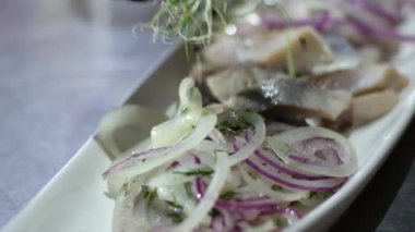 Tabakta ringa balığı servis et. Mikroyeşillik fileto ile süsle. Tabakta parçalara ayır. İsteyen istemciye sunmadan önce aperatif sunumunun son detaylarını tamamlayan dikkatli usta