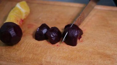 Pancar, tahta bir kesme tahtasıyla kesiliyor. Bıçaklı bir kadın pancarı dilimliyor. Yakın plan. Yüksek kalite 4k görüntü