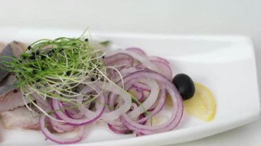 Tabakta ringa balığı servis et. Restoranda yemek pişir. Temizlenmiş filetolar tabakta parçalara ayrılsın. İsteyen istemciye sunmadan önce aperatif sunumunun son detaylarını tamamlayan dikkatli usta