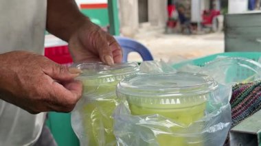 Karanlık eller ve ben Asyalı bir adam olarak bir sazlıktan tropikal bir içecek yapıyoruz ve bardaklara pipet takıp Asya sokaklarında fakirlik içiyoruz. Yüksek kalite 4k görüntü