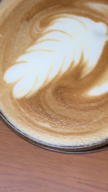 Latte sanat kahvesi makroya dönüşür, sanat kahvecisi kahve fincanında kahve yapar, müşteriye de kafe tezgahında kahve yapar. Erkek kahveci garson müşteriye sütlü sıcak içecek servisi yapıyor. Küçük işletme
