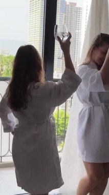 Kadınlar pencereyi kutluyor. Pencere kenarındaki beyaz kısa bornozlar ellerinde bardaklarla dans ediyorlar. İki genç kadın bir bekarlığa veda partisini kutluyor. Gülüyorlar.