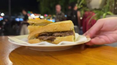 Banh mi bun, Vietnam köftesi. Beyaz bir plaka üzerinde yemek dağıtan elin 4K görüntüsüne bak.