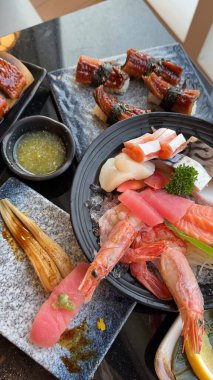 Geleneksel suşi seçimi modern bir tabakta soya sosu ve wasabi ile sunuluyor. dikey fotoğraflar somon suşili şehriye