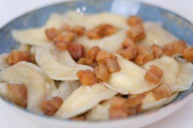 Bir tabak yumuşak hamur köftesi ve üstünde de kızarmış pastırma var. Bu doyurucu yemek, geleneksel lezzet ve dokuları sergiliyor. Yüksek kalite fotoğraf