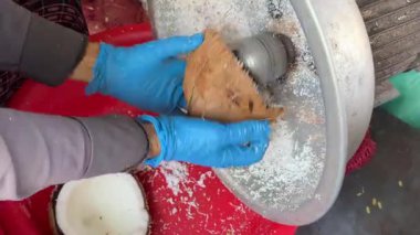 Eldivenli Asyalı kadın hindistan cevizinden hindistancevizi talaşı çıkartıyor. Hindistan cevizi, Asya pazarında meyve topluyor. Yüksek kalite 4k görüntü