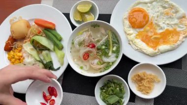 Masanın üzerinde duran Vietnamlı geleneksel çorba hobisine farklı baharatlar verin. Asya Oteli 'ndeki diğer besin yumurtalarının sağlıklı kahvaltı büfesinde limon ve kırmızı biber ekleyin. Yüksek kalite