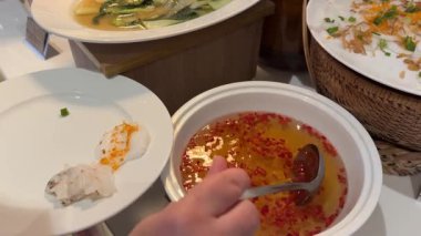 Asya yemeklerinin üzerine kırmızı biber ve balık sosu dökmek için otel restoranının baharatlı yemeklerine farklı soslar koymak için. Yüksek kalite 4k görüntü