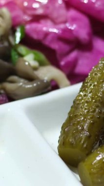 Aşçı beyaz bir tabakta salatalık turşusu ve siyah eldiven servis eder. Yüksek kalite 4k görüntü