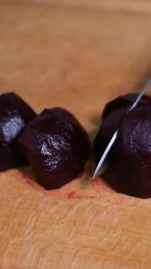 Pancar, tahta bir kesme tahtasıyla kesiliyor. Bıçaklı bir kadın pancarı dilimliyor. Yakın plan. Yüksek kalite 4k görüntü