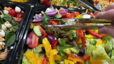 Kapalı alandaki açık büfe yemekleri için çeşitli taze salatalar sergileniyor. Yüksek kalite 4k görüntü