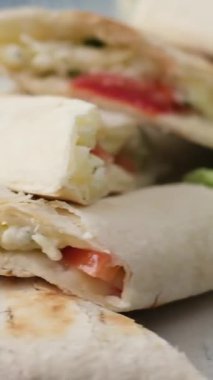 Taze sebze ve beyaz arka planda tavuk dürümü yanında doğranmış domates ve yeşillik. Peynirli ve domatesli lavaş.