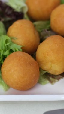 Peynir toplarını ayçiçeği yağında kızartma süreci ketçaplı, yağlı, beyaz bir tabağa koy.