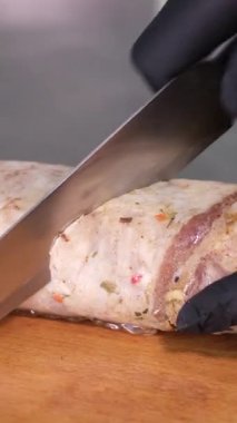 Eller bıçakla bir ahşabın üzerindeki sosisi doğruyor. Köfteyi kes.