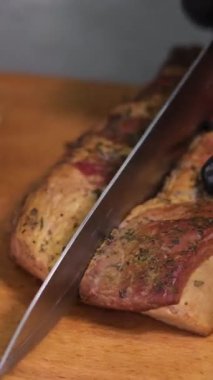 Pitmaster, ticari restoran mutfağında Teksas barbekü bifteğini ince ince dilimliyor. Lezzetli, yağlı, geleneksel tütsülenmiş göğüs etini kesme tahtasına oyuyor. Yavaş çekimde tütsülenmiş göğüs eti.
