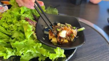 Asyalı farklı yemek çubukları soya peynirini siyah tabakta tutar büfe restoranında yemek yer sağlıklı yemekler baharatlı olur. Yüksek kalite 4k görüntü