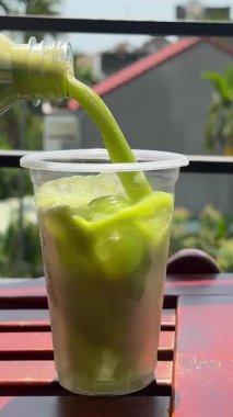 Ahşap masaya, kereviz, salatalık ve ıspanakla birlikte yeşil detoks smoothie döküyorum. Kahvaltıda sağlıklı organik karışım. Dikey video, yakın plan. Yüksek kalite 4k görüntü